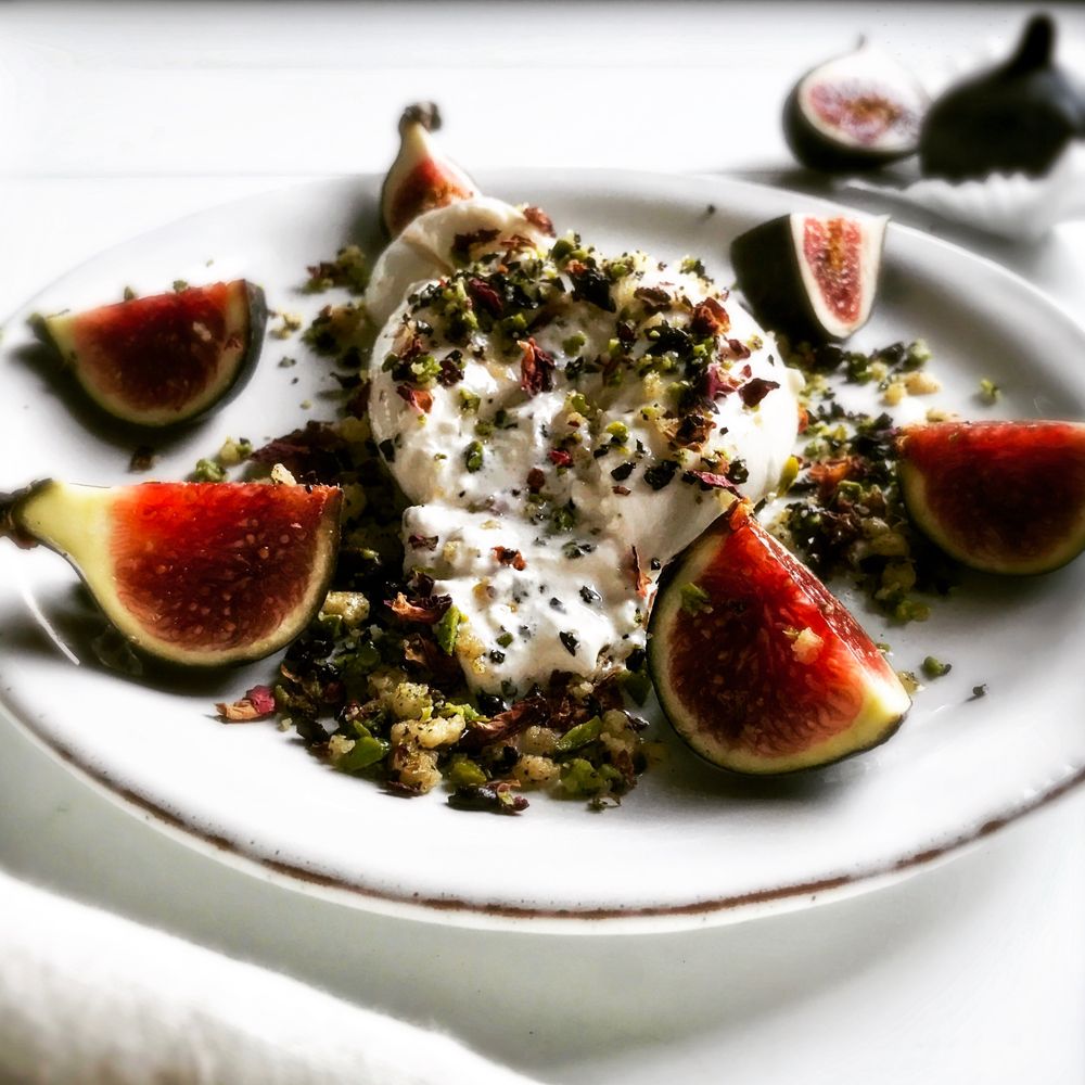 Rezeptbild: Frische Feigen und Burrata mit einem Krokant aus Pistazien, Kaffeebohnen und Rosenblättern