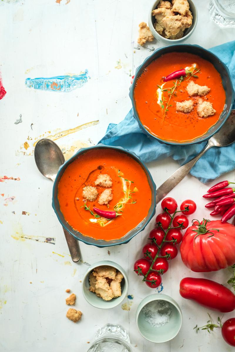 Rezeptbild: aromatische sommersuppe mit ofengerösteten tomaten und herzhaften crumbles aus manchegokäse, pinienkernen und thymian